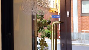 Entrada d'hotel amb una porta de vidre decorativa, un senyal que diu "TIRARE" i un pom d'elefant de bronze.