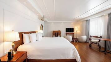 Una habitación de hotel con una cama grande, lámparas de noche, un escritorio, una silla y un televisor.
