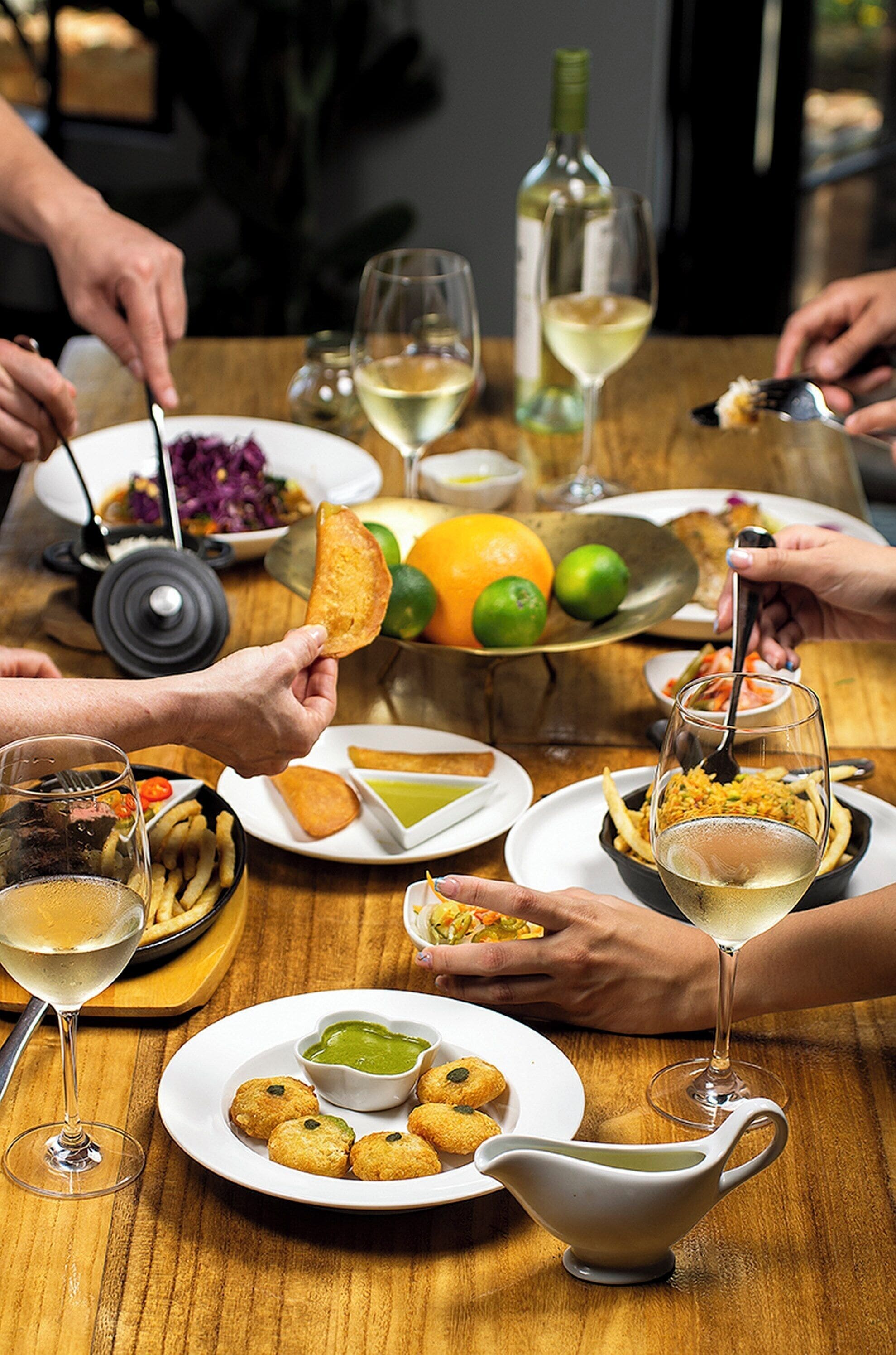 Une table à manger avec différents plats, des verres à vin et une bouteille de vin.