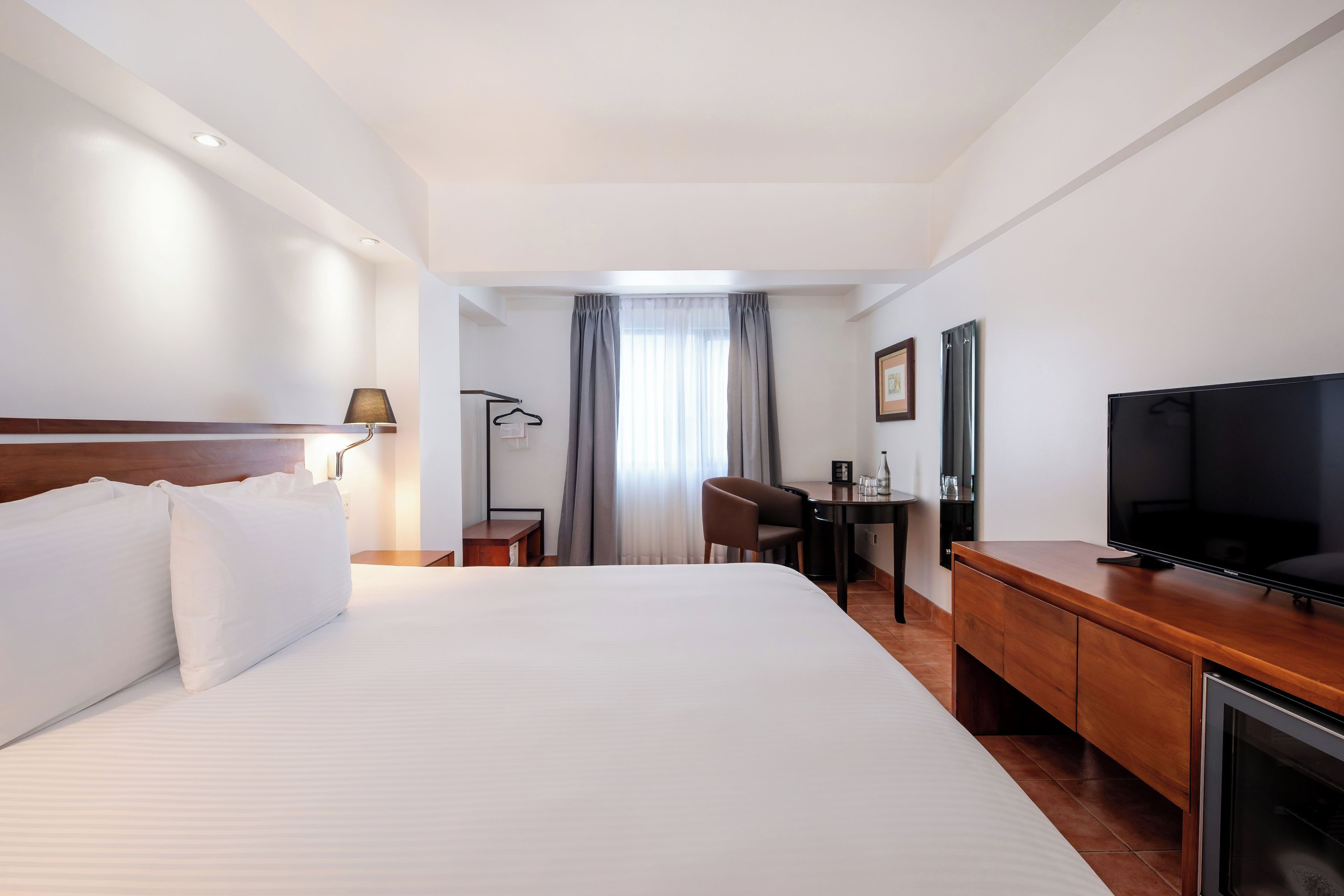 Ein Hotelzimmer mit einem großen Bett, einem Schreibtisch mit Stuhl, einem Fernseher und einem Kamin.