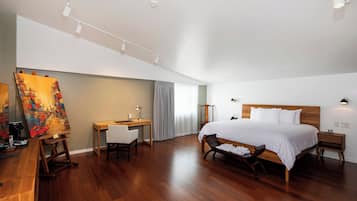 Ein geräumiges Schlafzimmer mit einem großen Bett, einem Schreibtisch und einem Malkasten mit einem Gemälde.