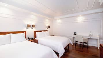 A hotel room with two beds, a desk, and a chair.