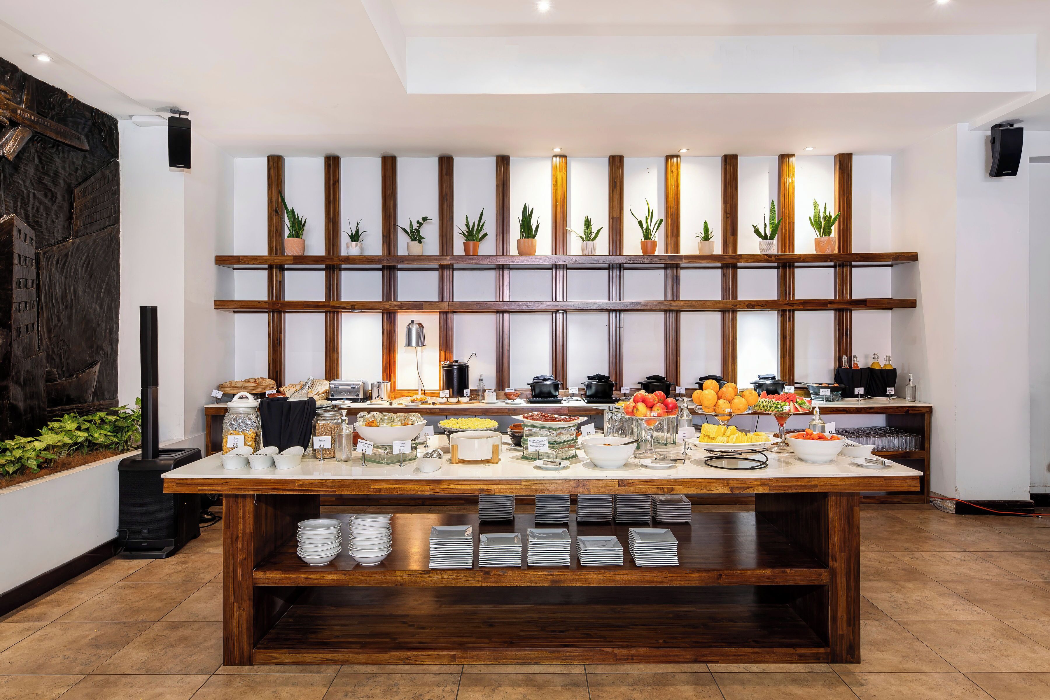 Un buffet garni de divers plats et une étagère en bois ornée de plantes en pot.