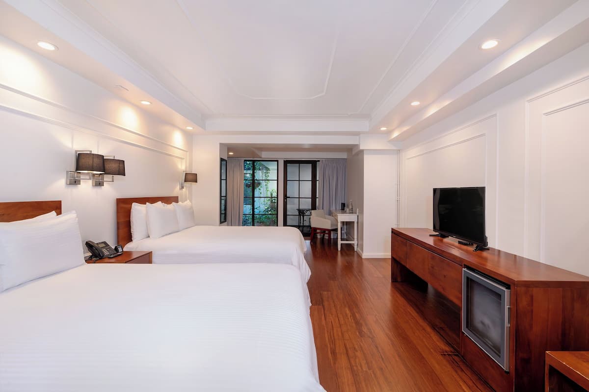 A hotel room with two beds, a TV, a desk, and a phone on the nightstand.