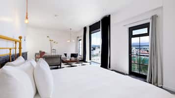 Quarto de hotel moderno com uma cama grande, uma escrivaninha e vista para a cidade.