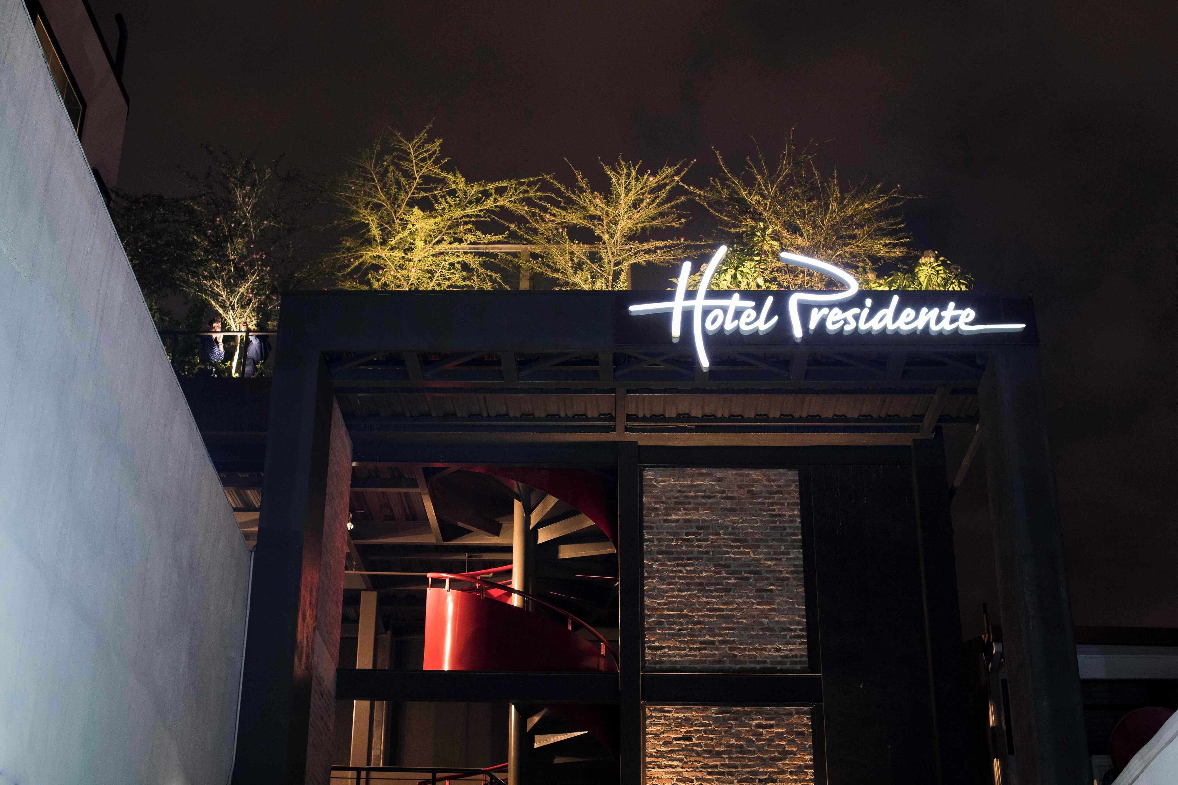 Ein Hotel Eingang mit einem Neonlichtschild, auf dem 'Hotel Presidente' steht.