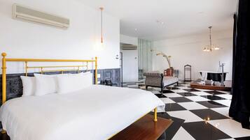 Ein modernes Hotelzimmer mit einem großen Bett, einem Schachbrettmuster-Boden, einem Schminktisch mit Spiegel und einem Sessel.