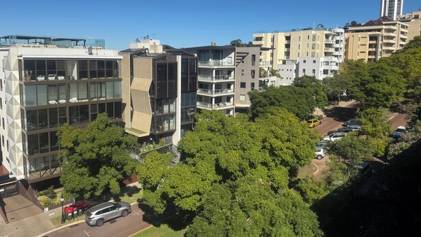 Una zona urbana moderna con edificios de varios pisos, incluyendo una estructura con fachada de vidrio destacada y un edificio alto con aguja.