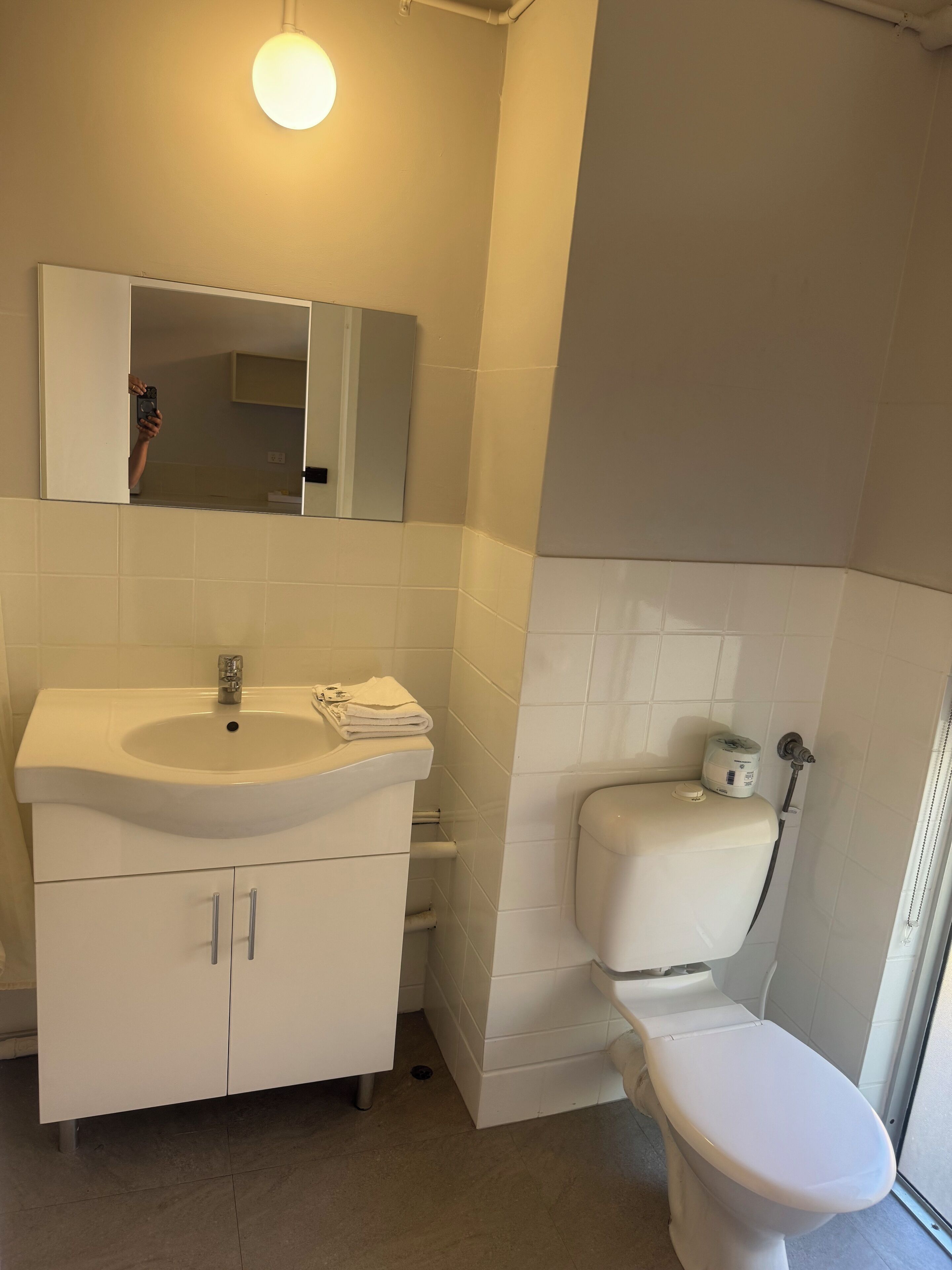 A bathroom with a white sink, mirror, and toilet.
