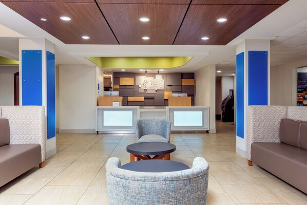 Um lobby moderno com balcão de atendimento, área de estar e teto de madeira com iluminação embutida.