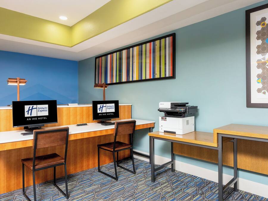 A hotel reception desk with two monitors, a printer, and a framed artwork on the wall.
