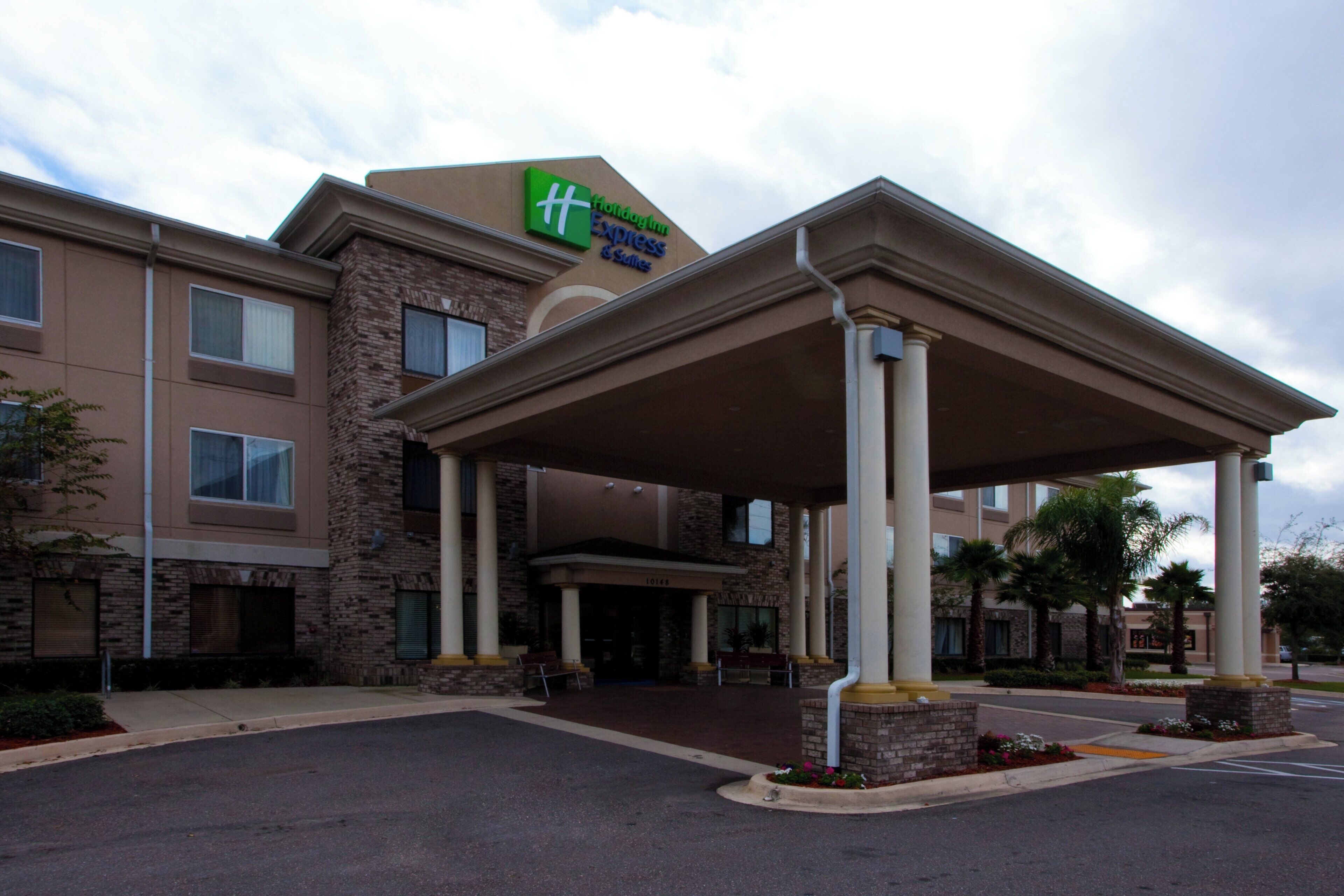 A hotel entrance with a covered walkway, a brick facade, and a sign for Holiday Inn Express & Suites.