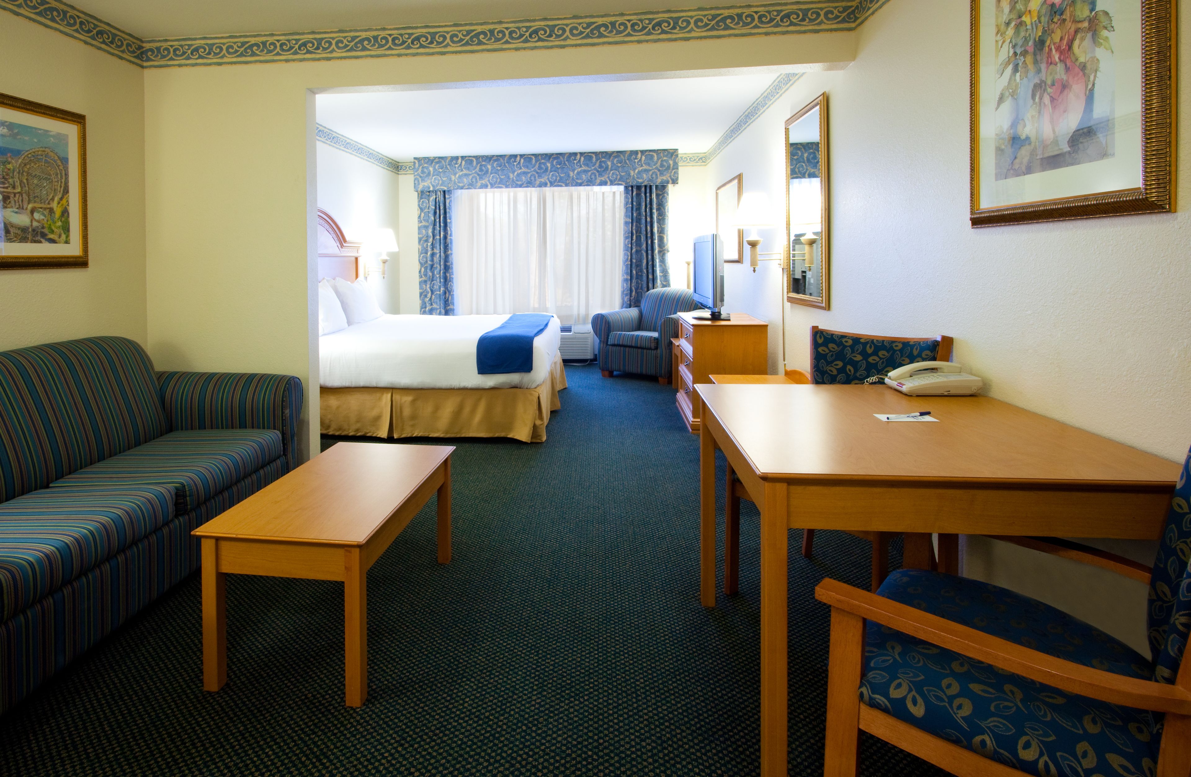 A hotel room with a bed, a sofa, a table, and a chair.