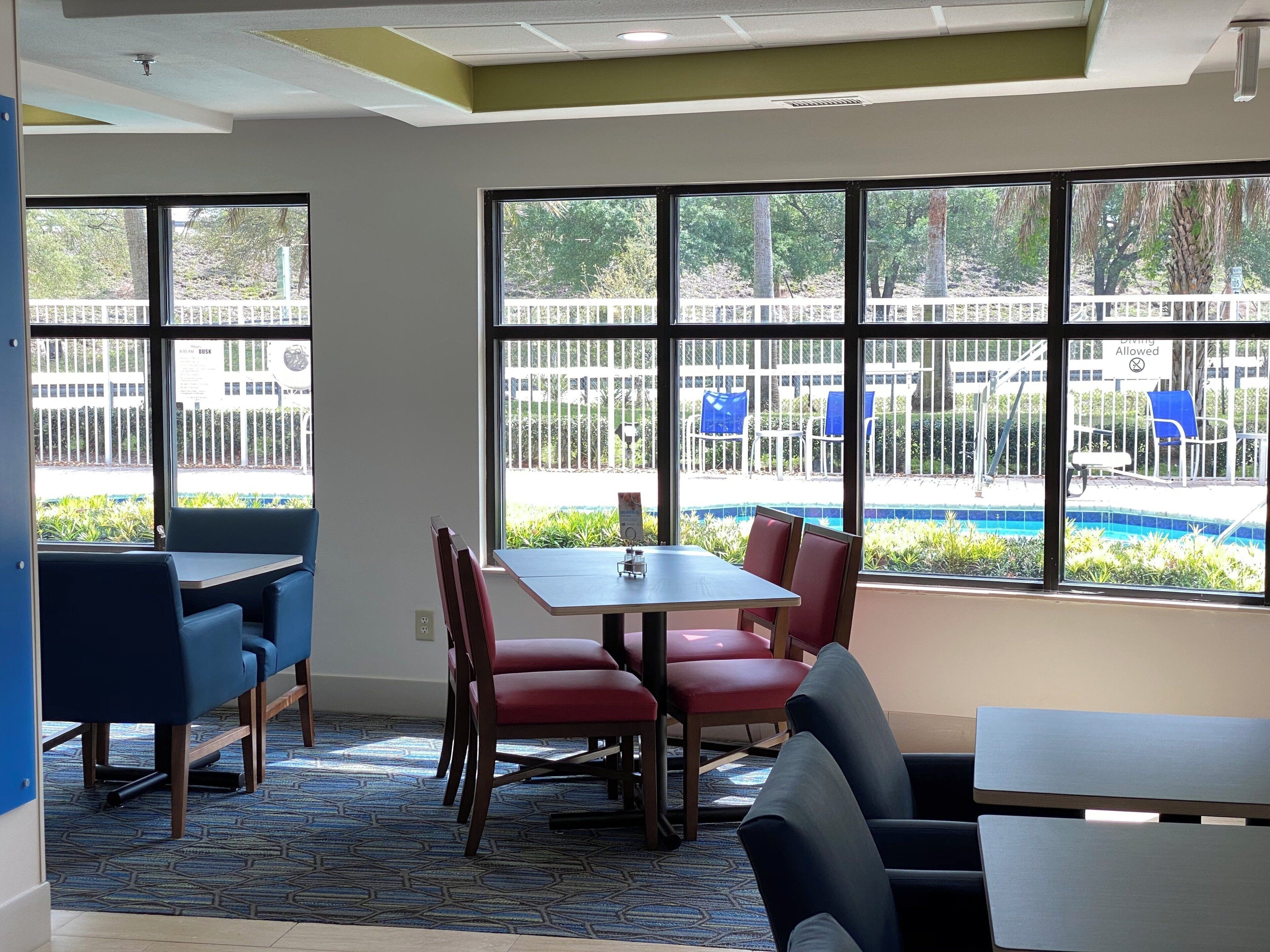 A room with a pool view, a table with chairs, and a blue carpet.