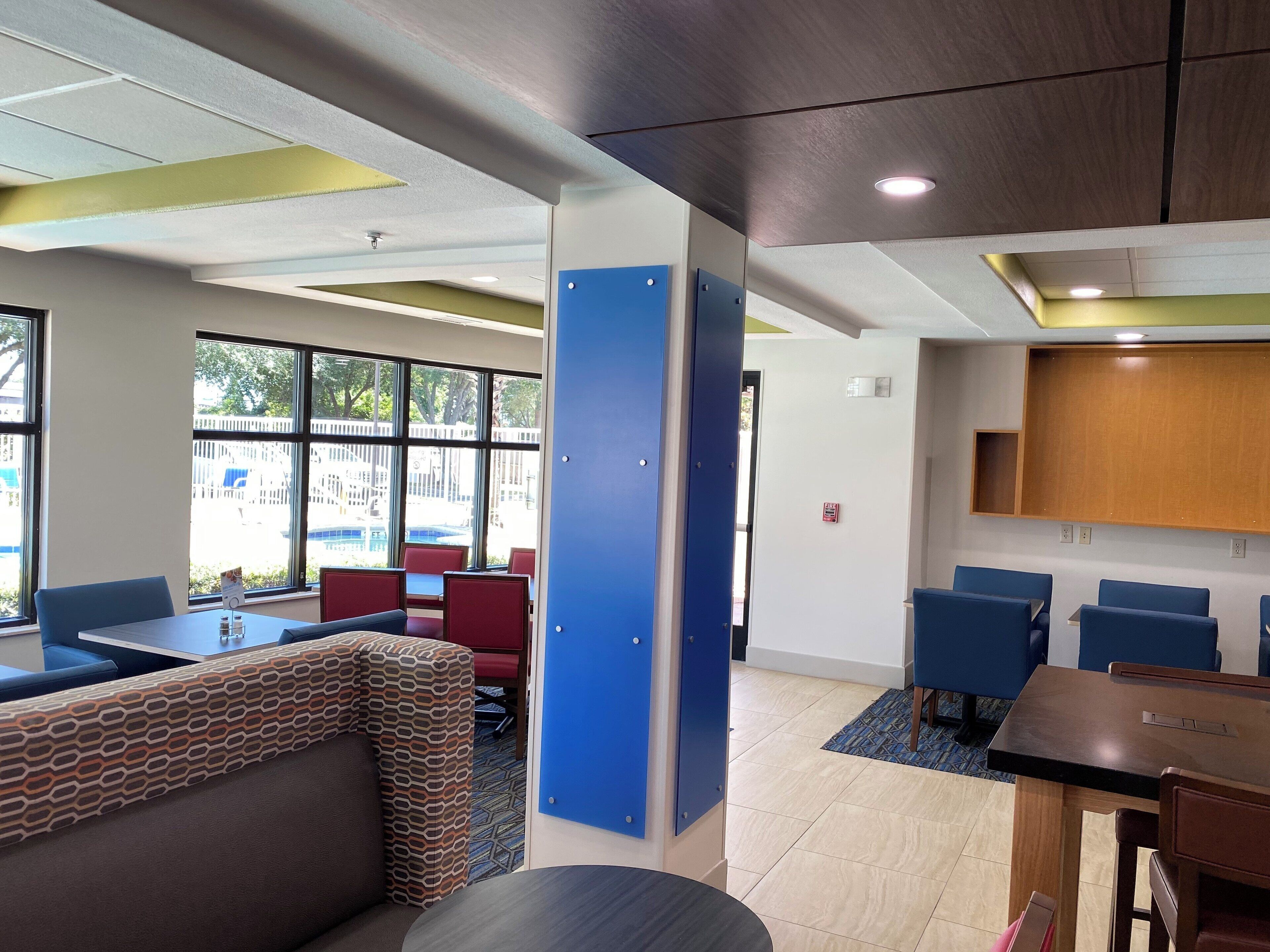 A modern interior with seating areas, a wooden cabinet, and large windows.