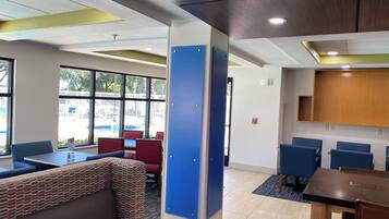 A modern interior with seating areas, a wooden cabinet, and large windows.