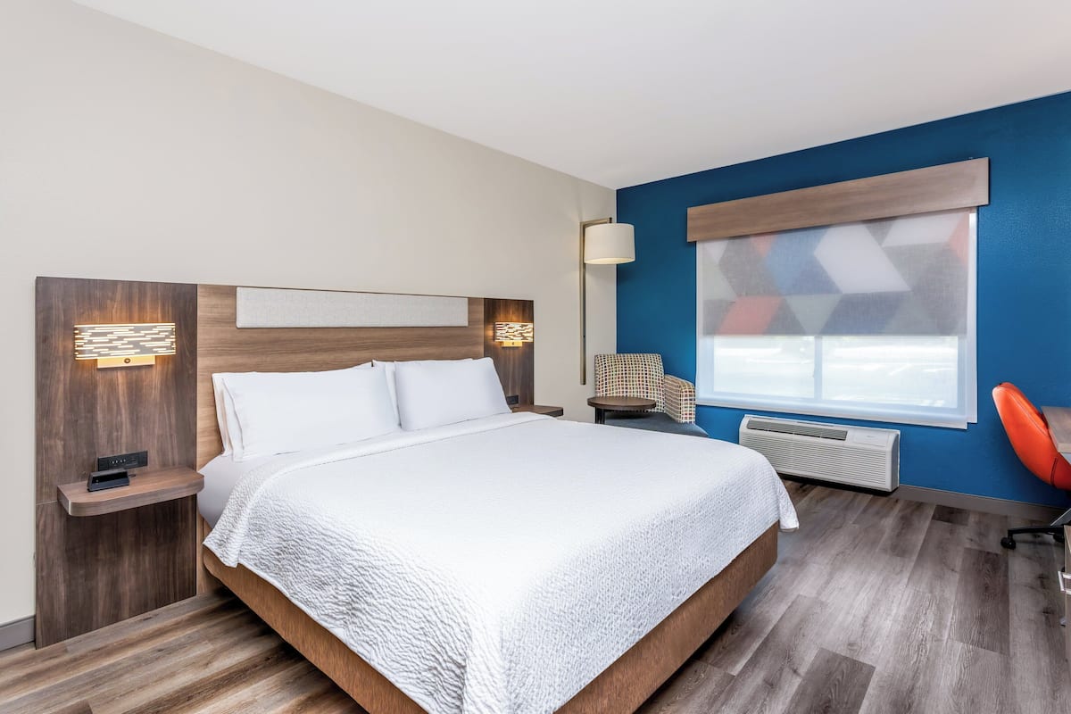 Ein modernes Hotelzimmer mit einem großen Bett, einem Schreibtisch und einem Sessel.