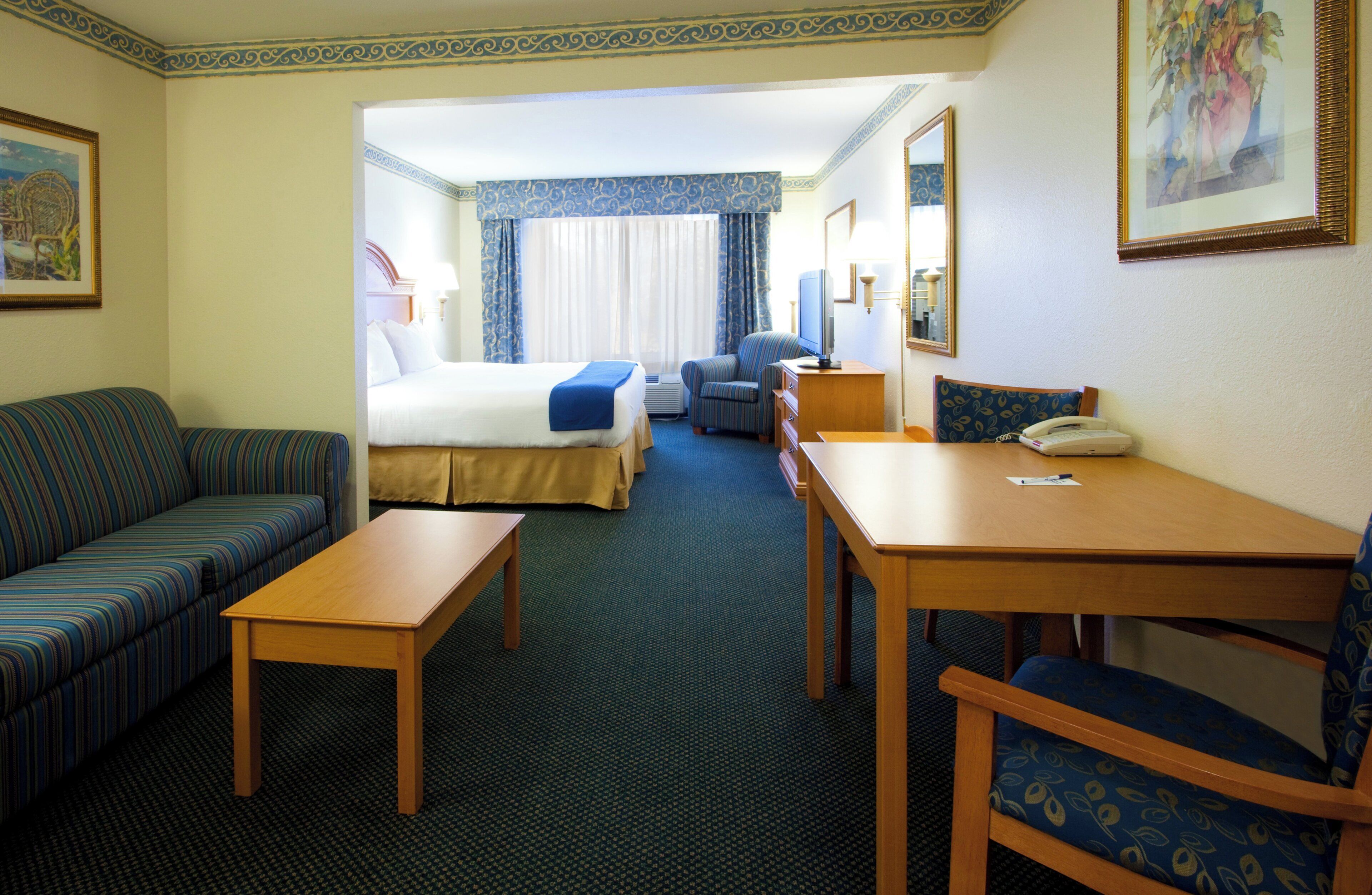A hotel room with a bed, a sofa, a desk, and a chair.