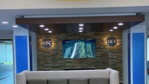 Un hall d’entrée moderne avec un canapé, une petite table et un grand écran fixé au mur.