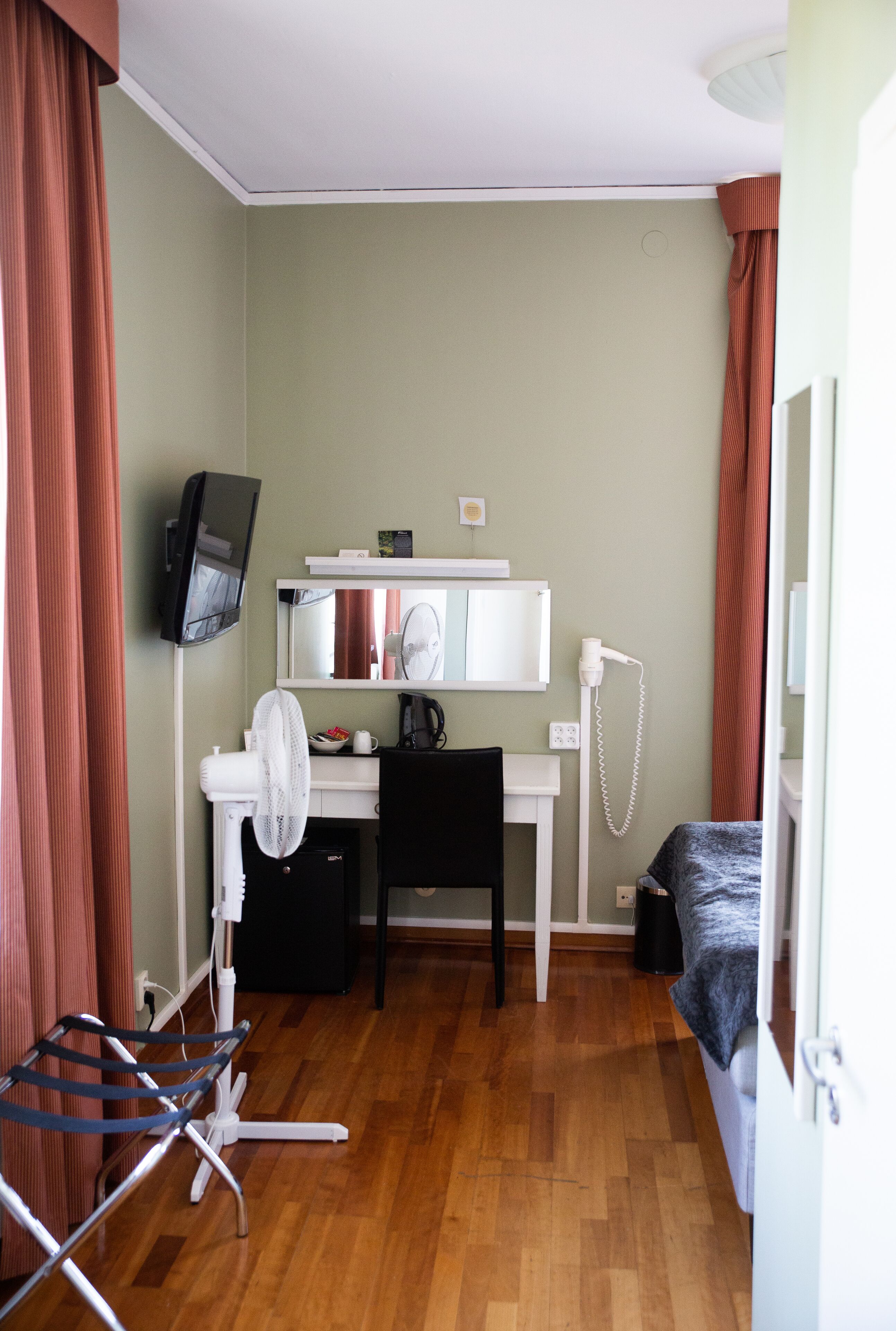 A compact room with a desk, chair, and a bed.