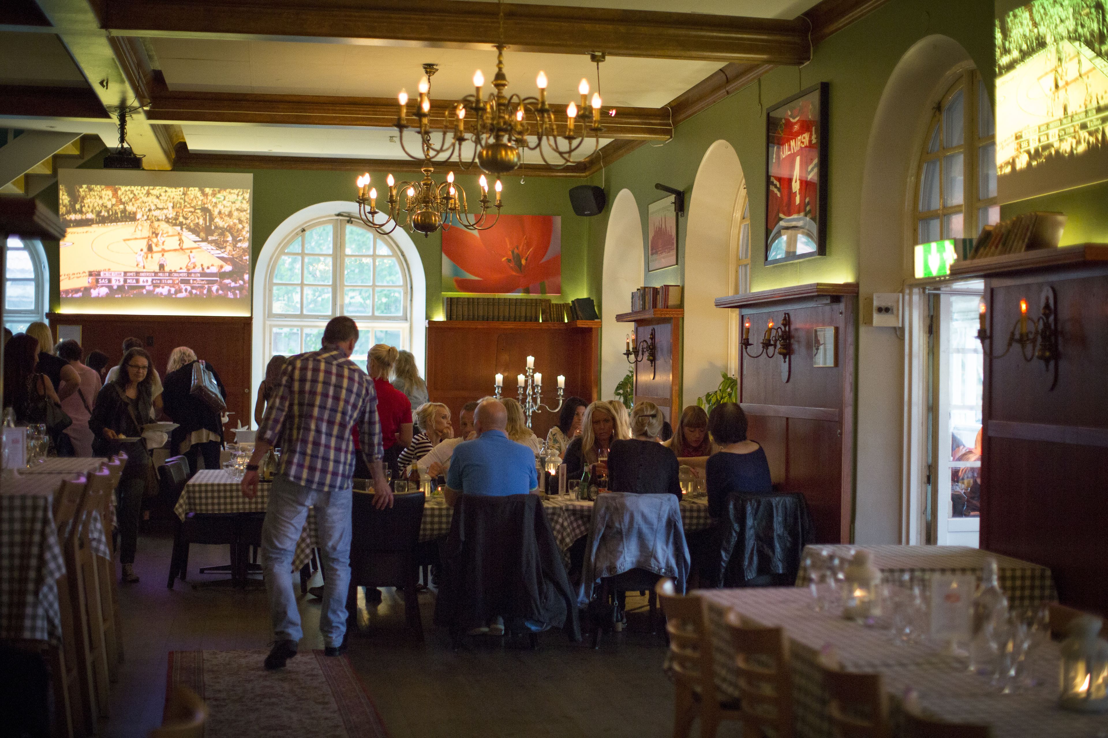 Een restaurant met meerdere tafels en stoelen, een kroonluchter en een groot raam met uitzicht.