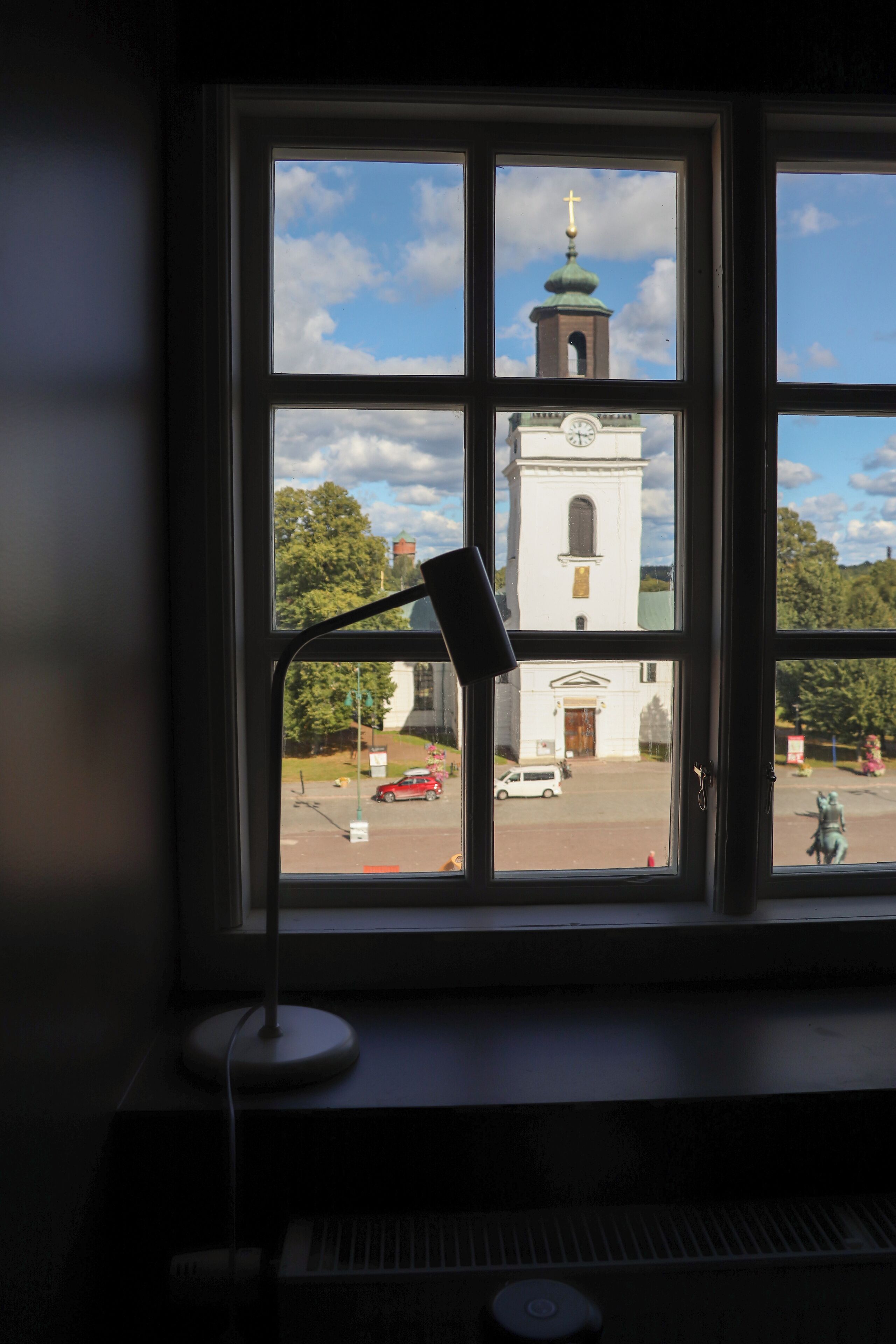 Ett fönster med utsikt över en kyrka och en gata.