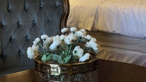 Una habitación de hotel con un cabecero capitonado, una cama con ropa blanca y dos lámparas de noche.