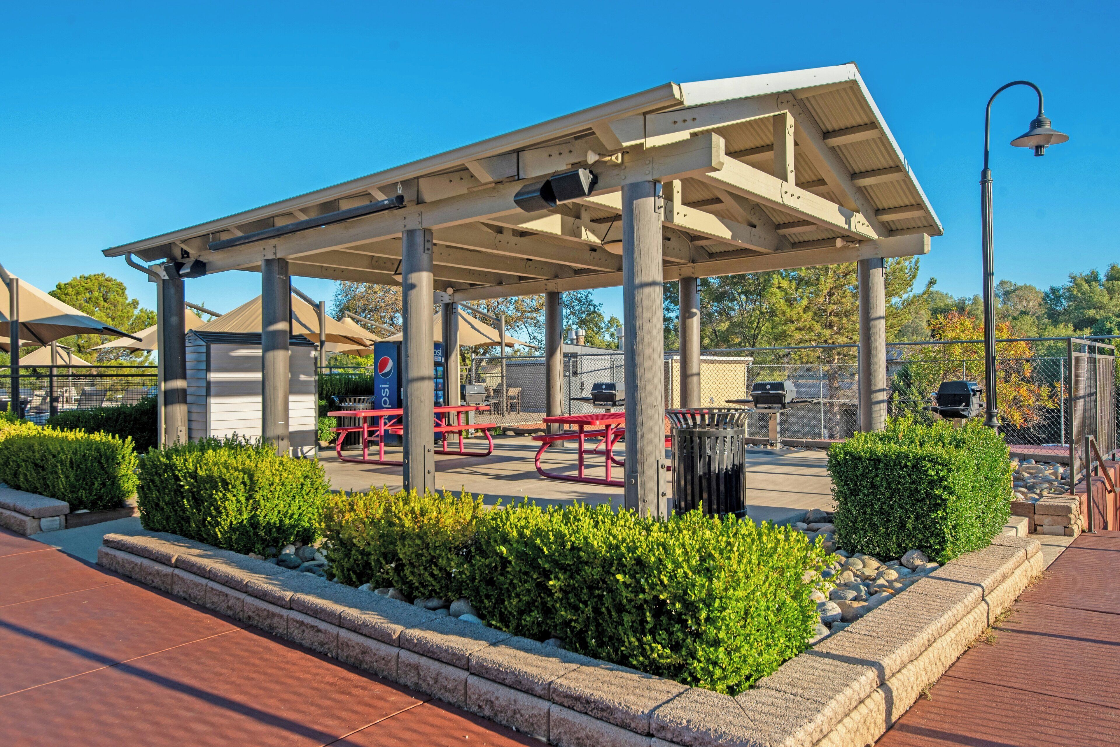 A covered outdoor area with picnic tables and a barbecue grill.