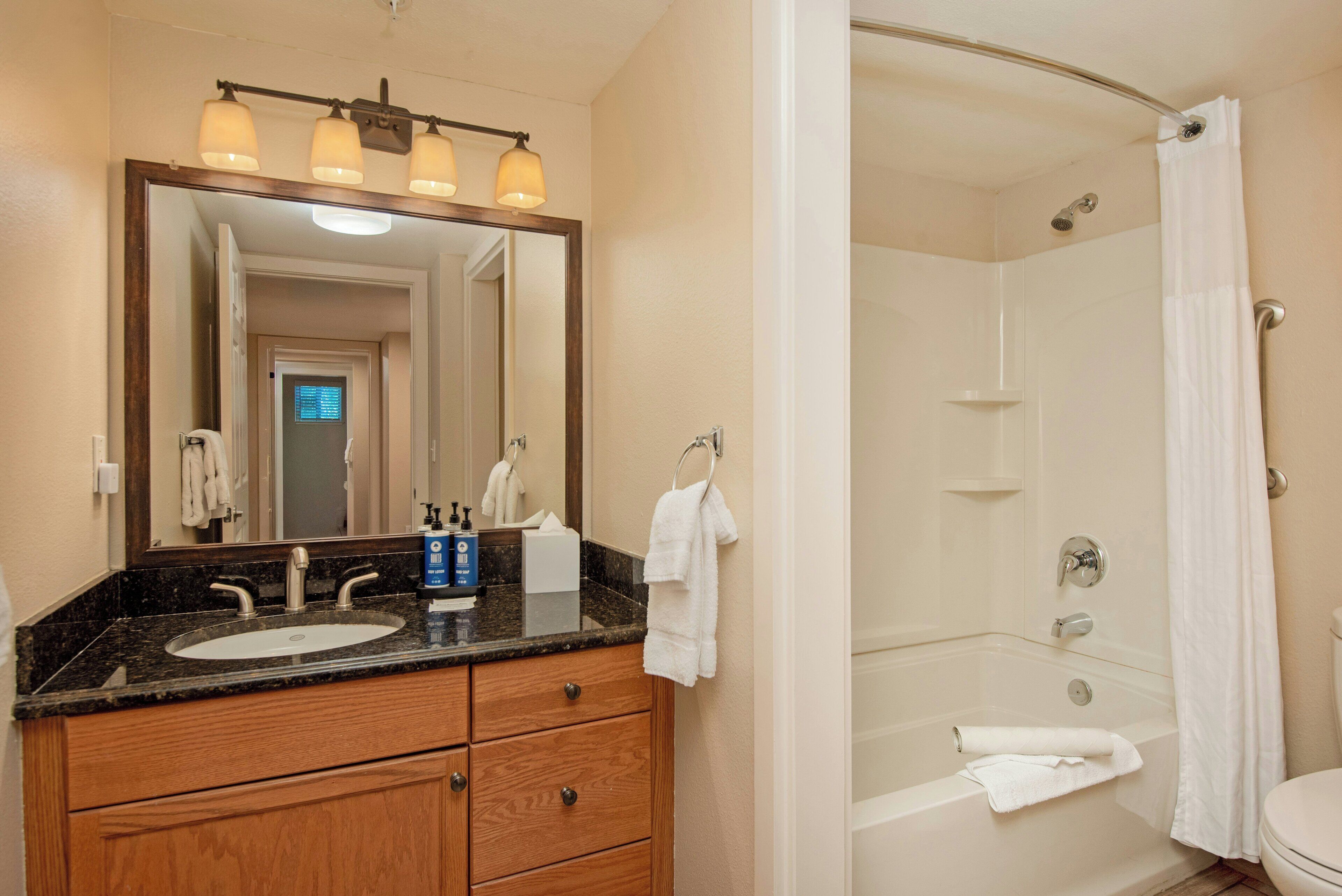 A bathroom with a sink, mirror, and shower.