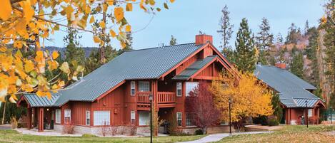 A large, red wooden building with a green roof, multiple windows, and a porch.