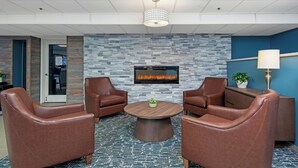 A lobby with leather chairs, a round wooden table, a stone wall, a fireplace, and a ceiling light fixture. - Worldmark Birch Bay (Blaine)