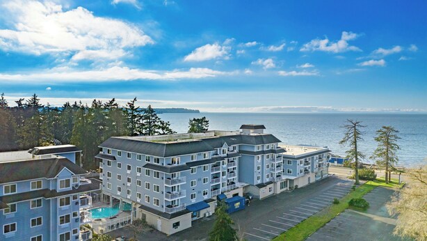 A multi-story hotel with a swimming pool, parking lot, and a view of the ocean. - Worldmark Birch Bay (Blaine)
