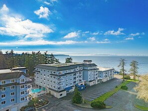A multi-story hotel with a swimming pool, parking lot, and a view of the ocean. - Worldmark Birch Bay (Blaine)