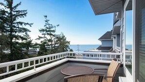 A balcony with a view of the ocean, a table, and two chairs. - Worldmark Birch Bay (Blaine)