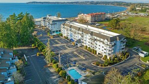 A multi-story hotel with a swimming pool, parking lot, and a view of the sea. - Worldmark Birch Bay (Blaine)