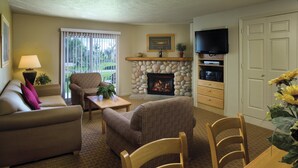 A living room with a fireplace, a television, and a dining area with a table and chairs. - WorldMark Bear Lake (Garden City)
