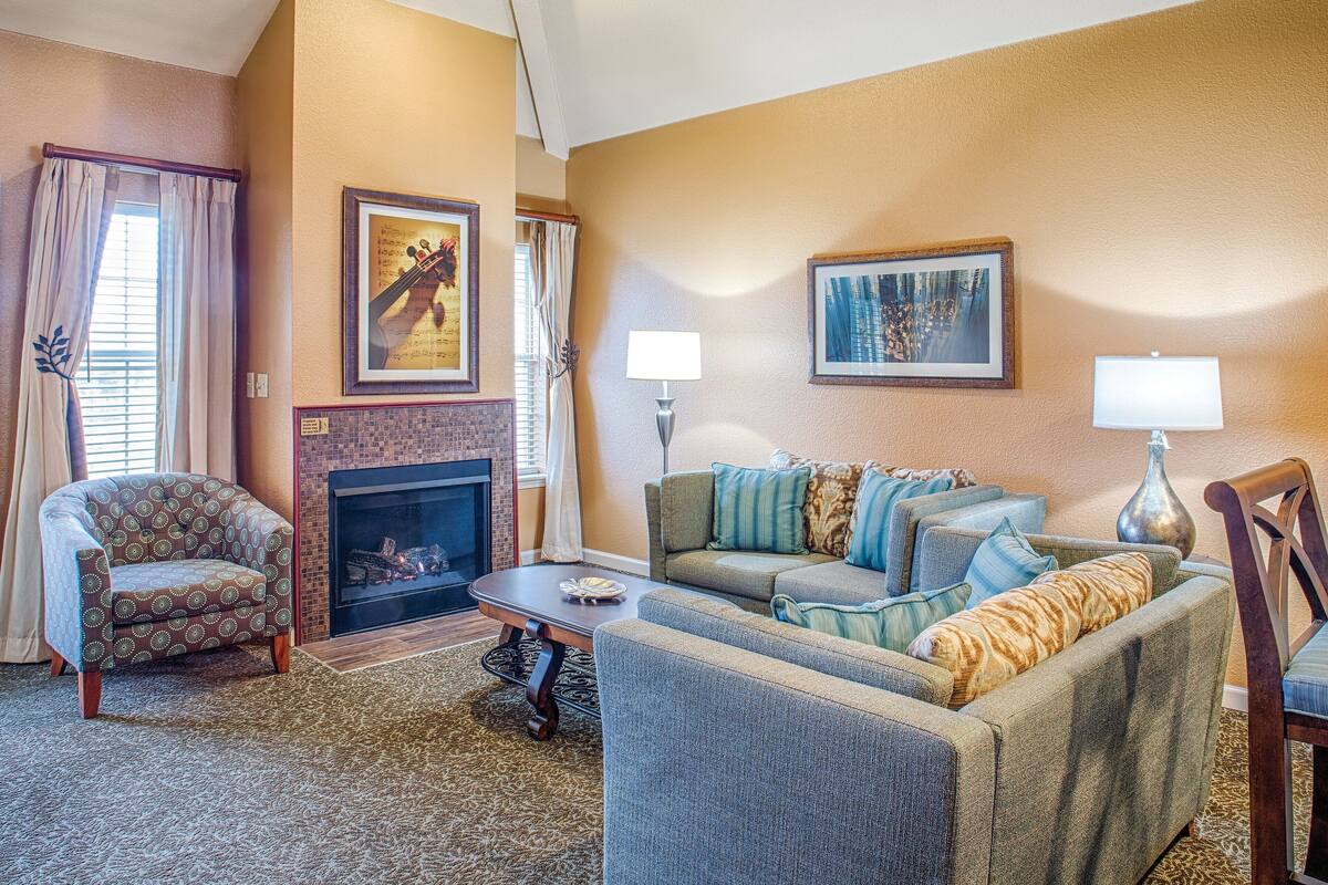 A living room with a fireplace, a sofa, a chair, and a lamp.