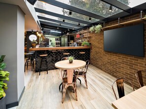 A modern outdoor dining area with a brick wall, a round table, and metal chairs. - ibis Curitiba Batel (Curitiba)