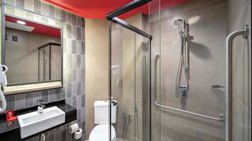 Un baño moderno con ducha de vidrio, inodoro blanco y lavamanos negro con espejo superior.