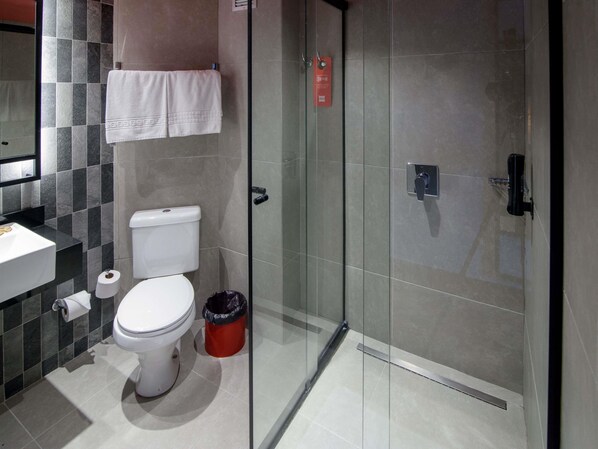 Un baño moderno con inodoro, lavabo y cabina de ducha de vidrio.