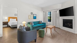 A hotel room with a bed, a sofa, a small table, a TV, and a fireplace. - Sonesta ES Suites Phoenix Goodyear (Goodyear)
