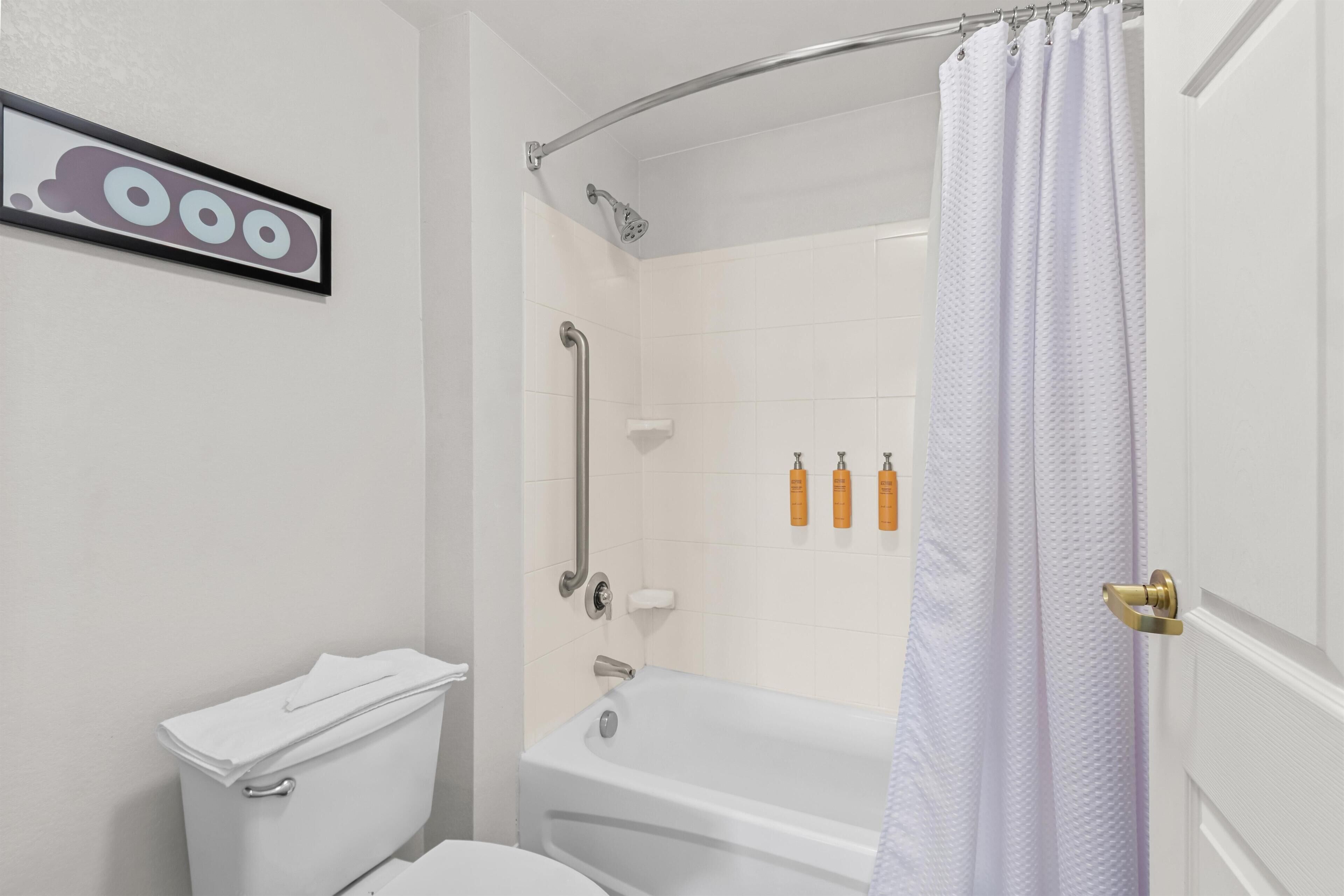 A bathroom with a toilet, a shower with a curved glass door, and a white bathtub.