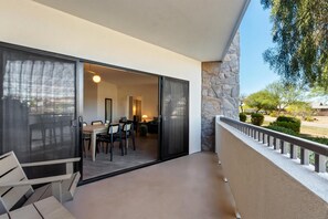 A balcony with a dining area, a stone wall, and a view of the outdoors.