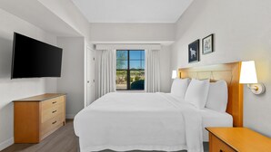 A hotel room with a bed, a TV, a desk, and a window with curtains. - Sonesta ES Suites Phoenix Goodyear (Goodyear)
