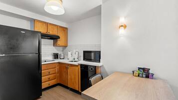 Una cocina moderna con un refrigerador negro, armarios de madera, un microondas y un lavavajillas.