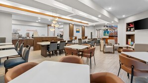 A modern restaurant with multiple dining areas, a counter, and a flat-screen TV mounted on the wall. - Sonesta ES Suites Phoenix Goodyear (Goodyear)