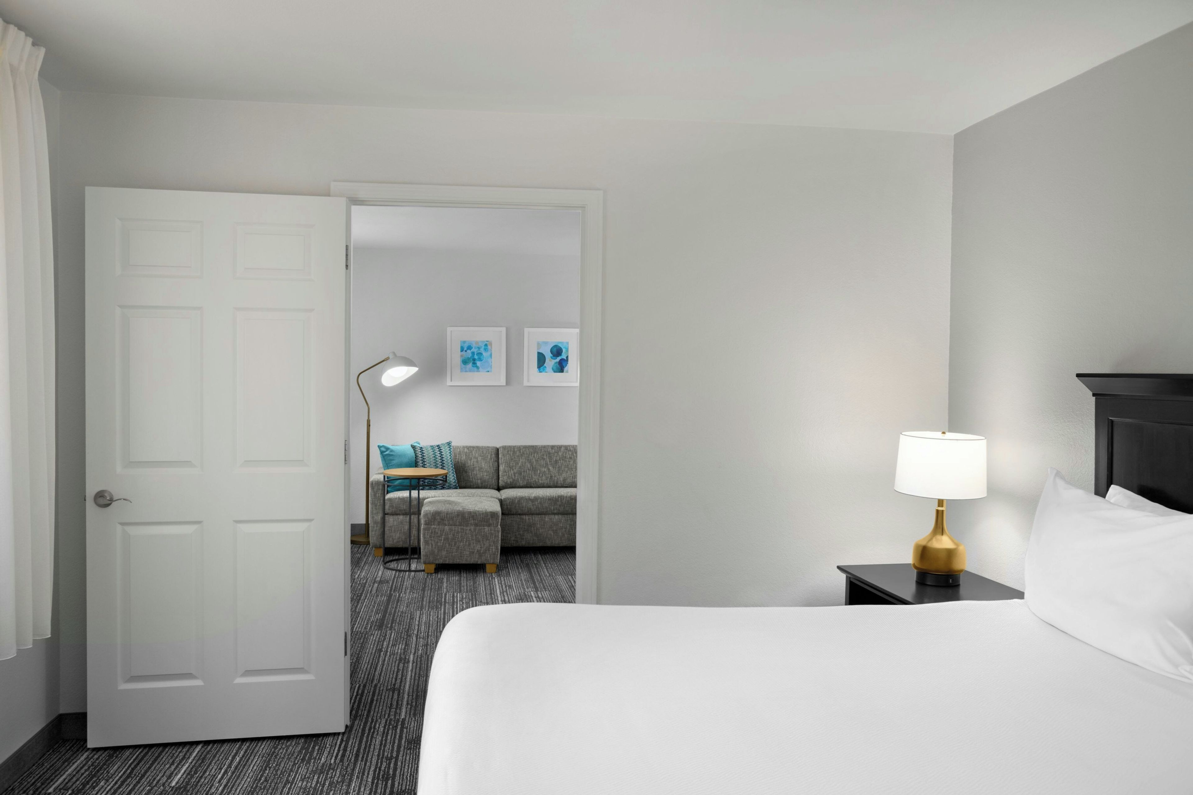 Una habitación de hotel con una cama, una mesita de noche con lámpara, un sofá y una mesa de centro.