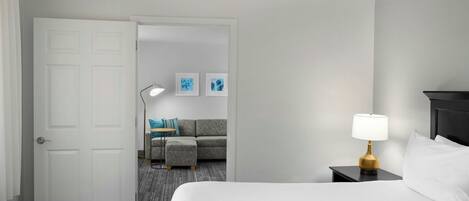 A hotel room with a bed, a nightstand with a lamp, a sofa, and a coffee table.
