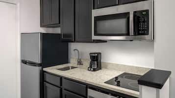 A compact kitchen with a refrigerator, microwave, coffee maker, sink, and dishwasher.