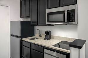 A compact kitchen with a refrigerator, microwave, coffee maker, sink, and dishwasher. - TownePlace Suites Marriott Joplin (Joplin)